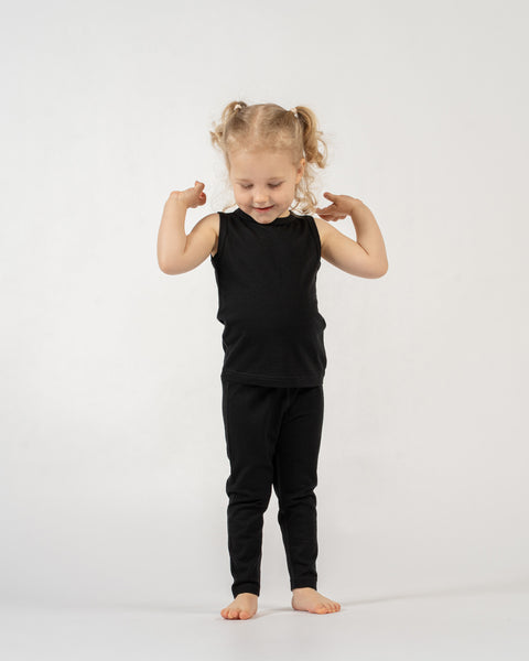Young girl wearing a black menique sleeveless top and pants on a white background