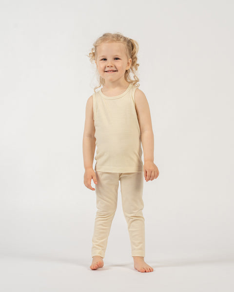 Child wearing a menique tank top and pants in the color natural on a white background