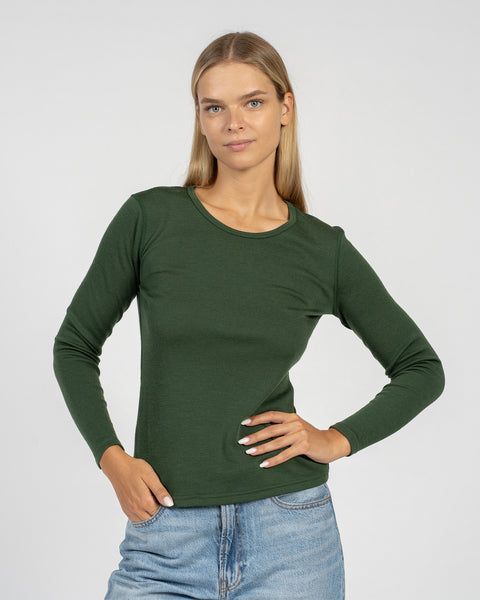 The menique women's merino wool dark green long sleeve top matched with classic light blue jeans, from the front.