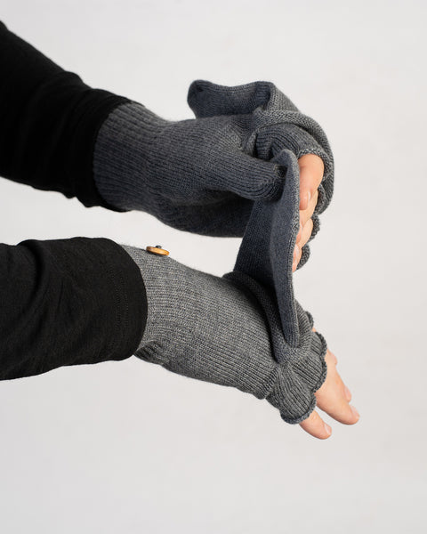 Hands demonstrating how to flip the mitten flap of gray convertible gloves over the fingers.