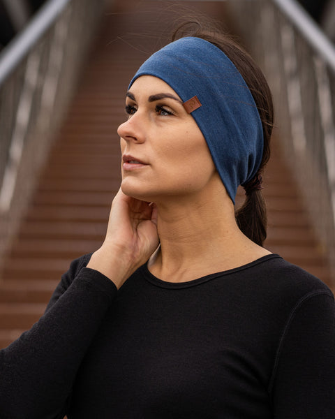 Woman wearing blue stretch headband, soft breathable fabric hair band for sports and everyday wear, minimalist unisex accessory styled outdoors
