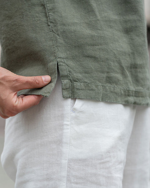 Close-up of a woman showing linen blouse in a stone green color.