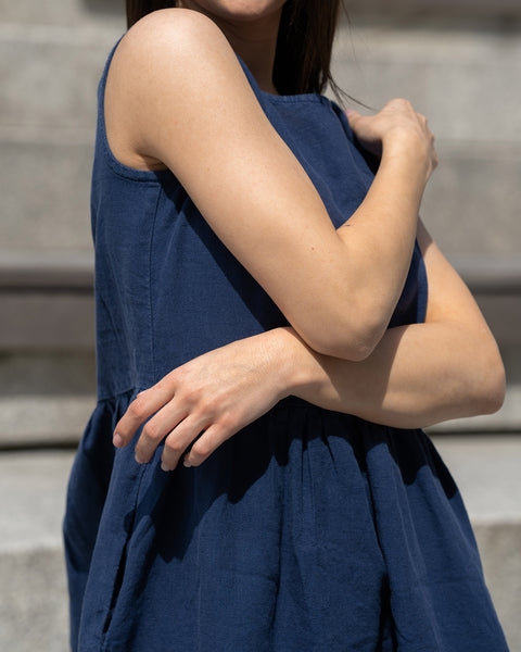 Close-up of a woman holding her hands on her shoulders, wearing linen dress storm blue color