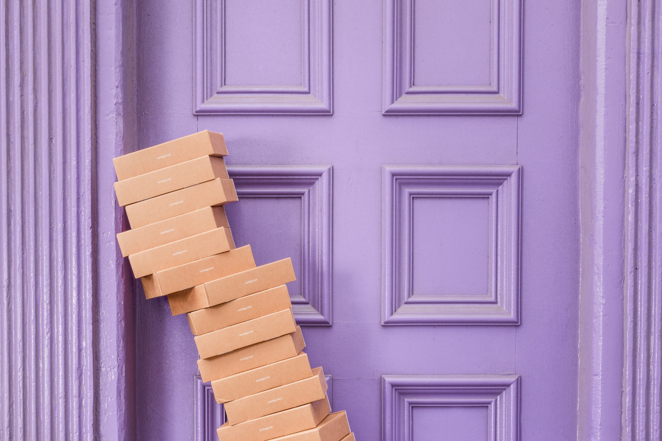online returns are costing the earth. Picture of many card boxes piled up next to the door