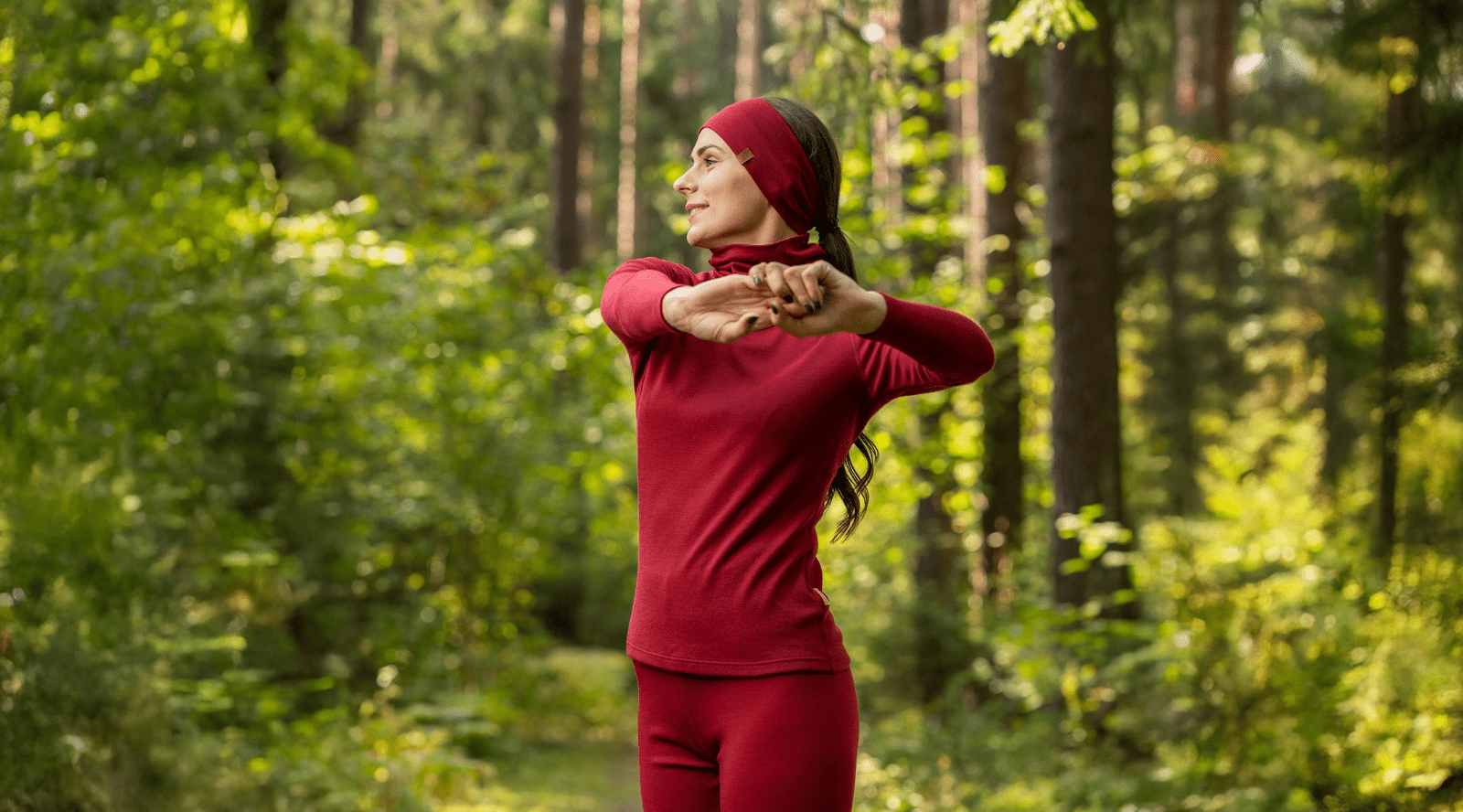 In the photo you can see woman standing, behind her there are exercising tools, such as weights. The woman is wearing black tank top with leggings made from organic 100% Merino Wool.