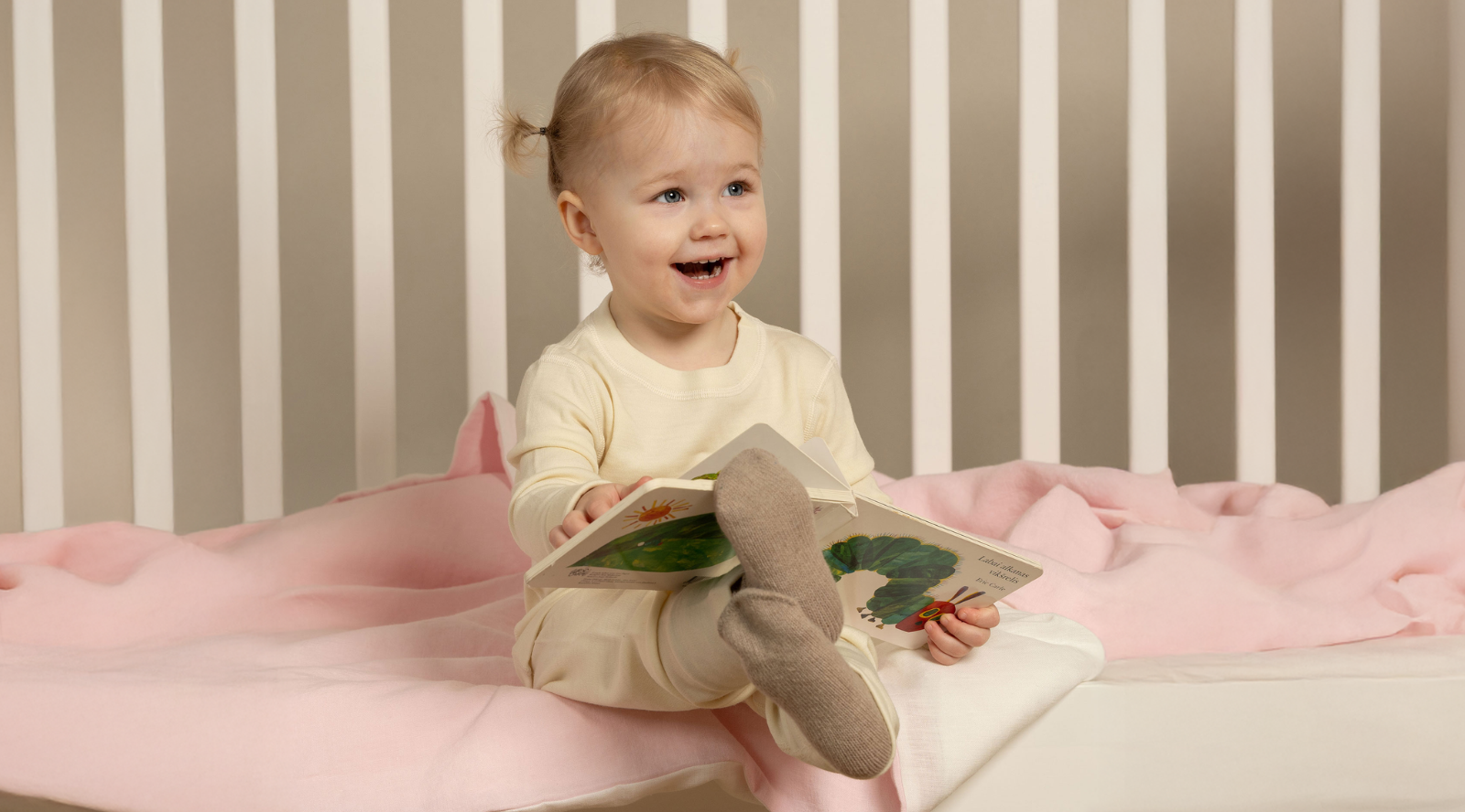 a little baby girl wearing a beige two piece set of merino clothing.