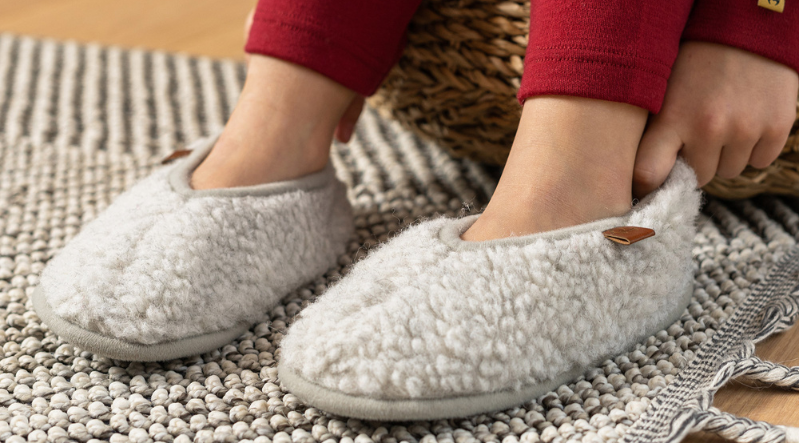 a child putting on merino wool slippers 