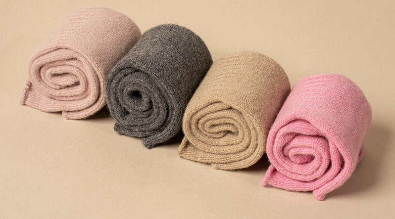 In this photo you can see rolled four pairs of socks, which are made from a mix of delicate Merino wool and cashmere. Candy pink, dark gray, creamy beige, and dusty pink tube socks.