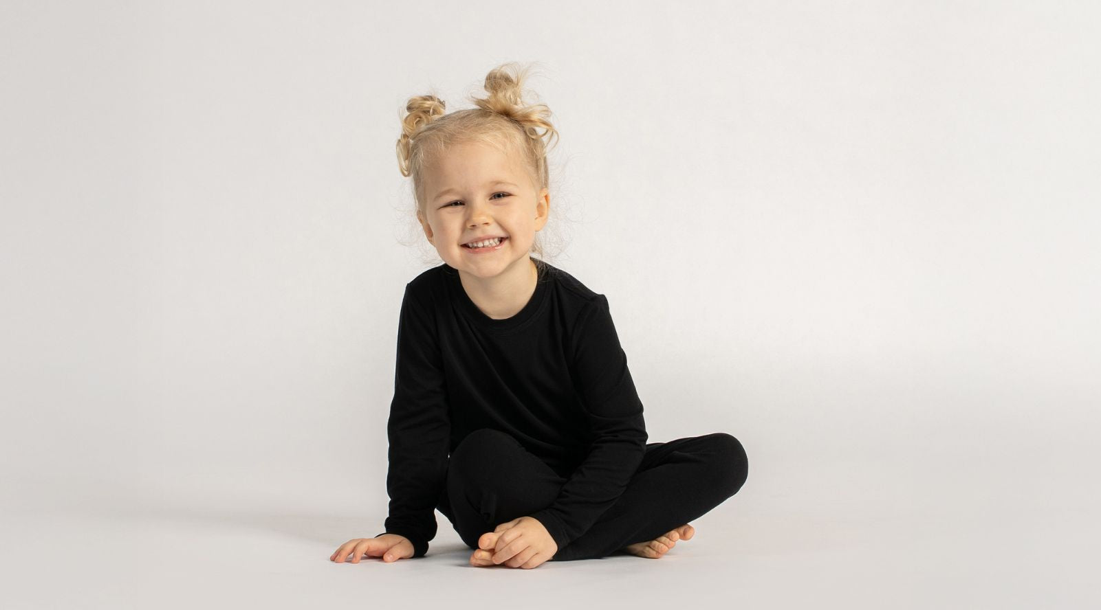 Child wearing a black outfit sitting on a white background