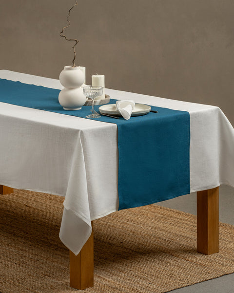 The cobalt blue linen table runner on top of a wooden table, captured in a close up picture from the corner of the table. 