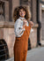 Woman with curly hair smiling while wearing cute almond brown nicci linen jumpsuit.