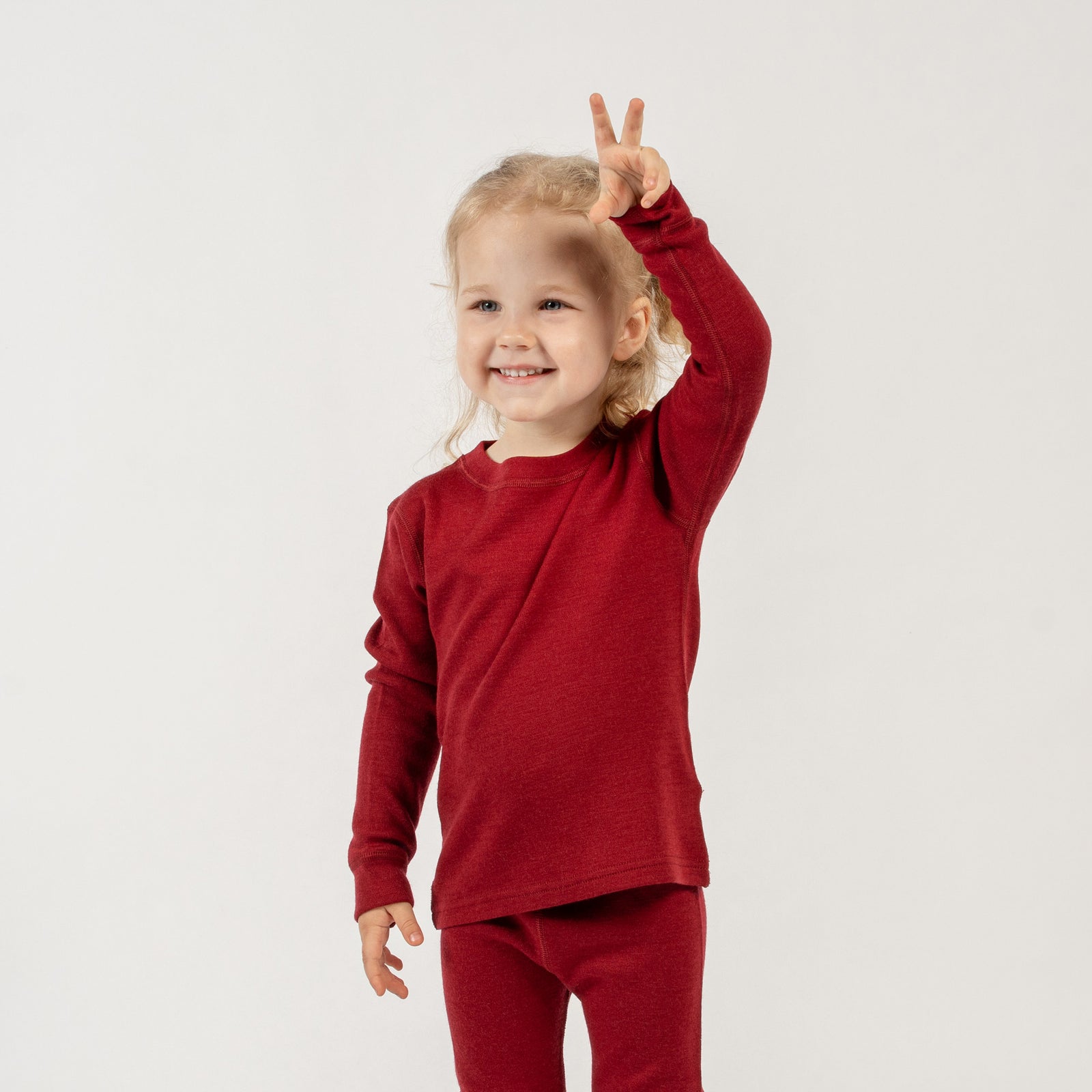 Front view of the kids' menique merino 250gsm long sleeve top, in royal cherry color, white background.