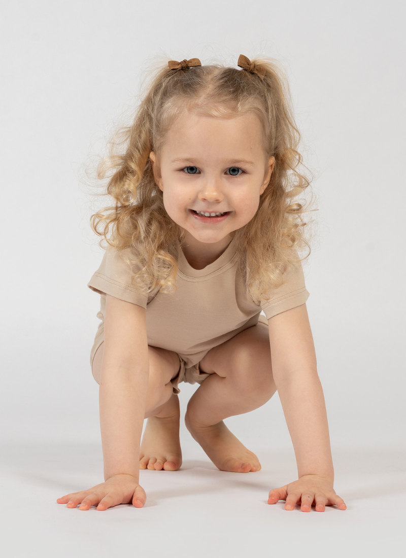 Child wearing a beige outfit on a white background