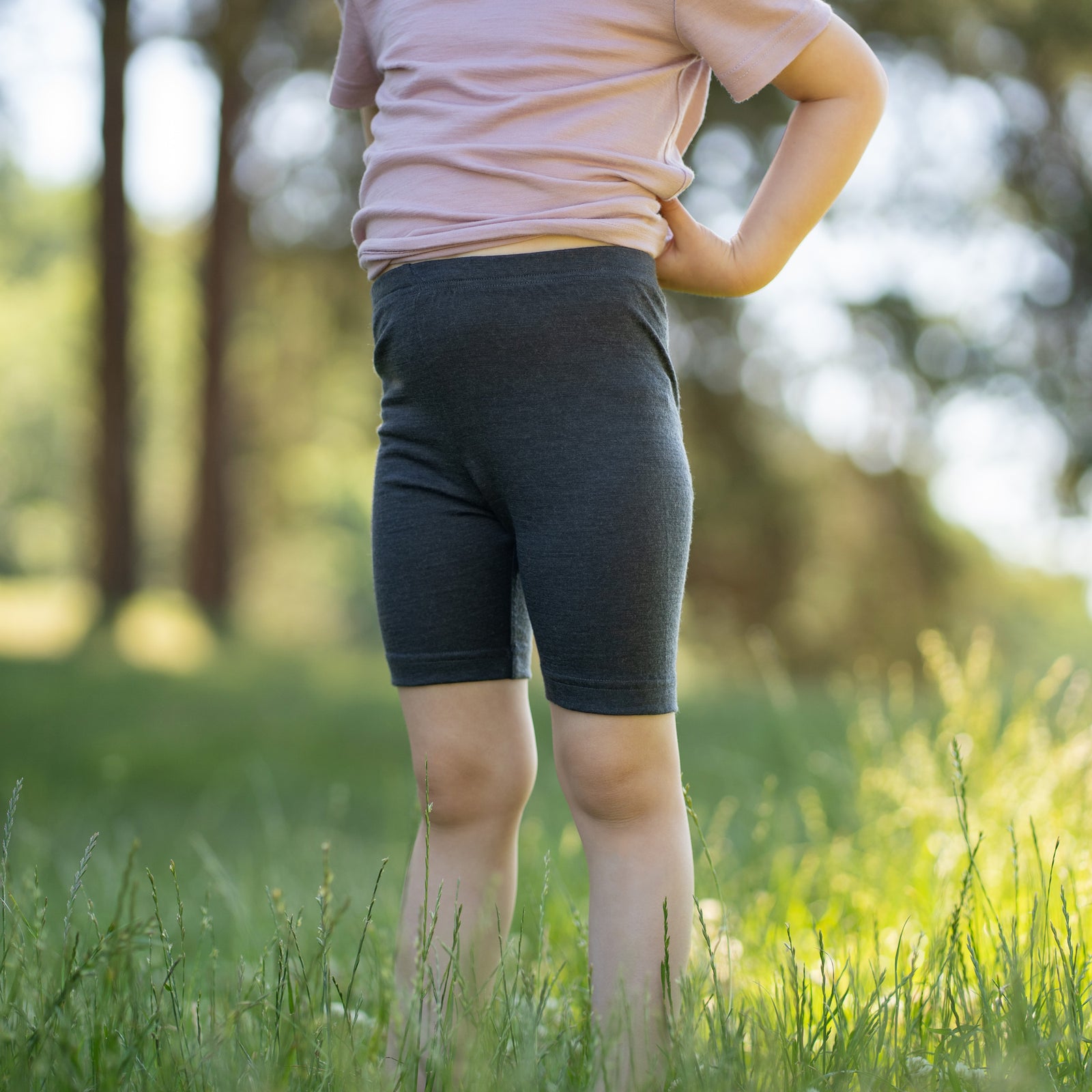 Two pairs of plain kids' cycling shorts laid flat side by side against a white background. The pair on the left is dark grey, and the pair on the right is light brown.