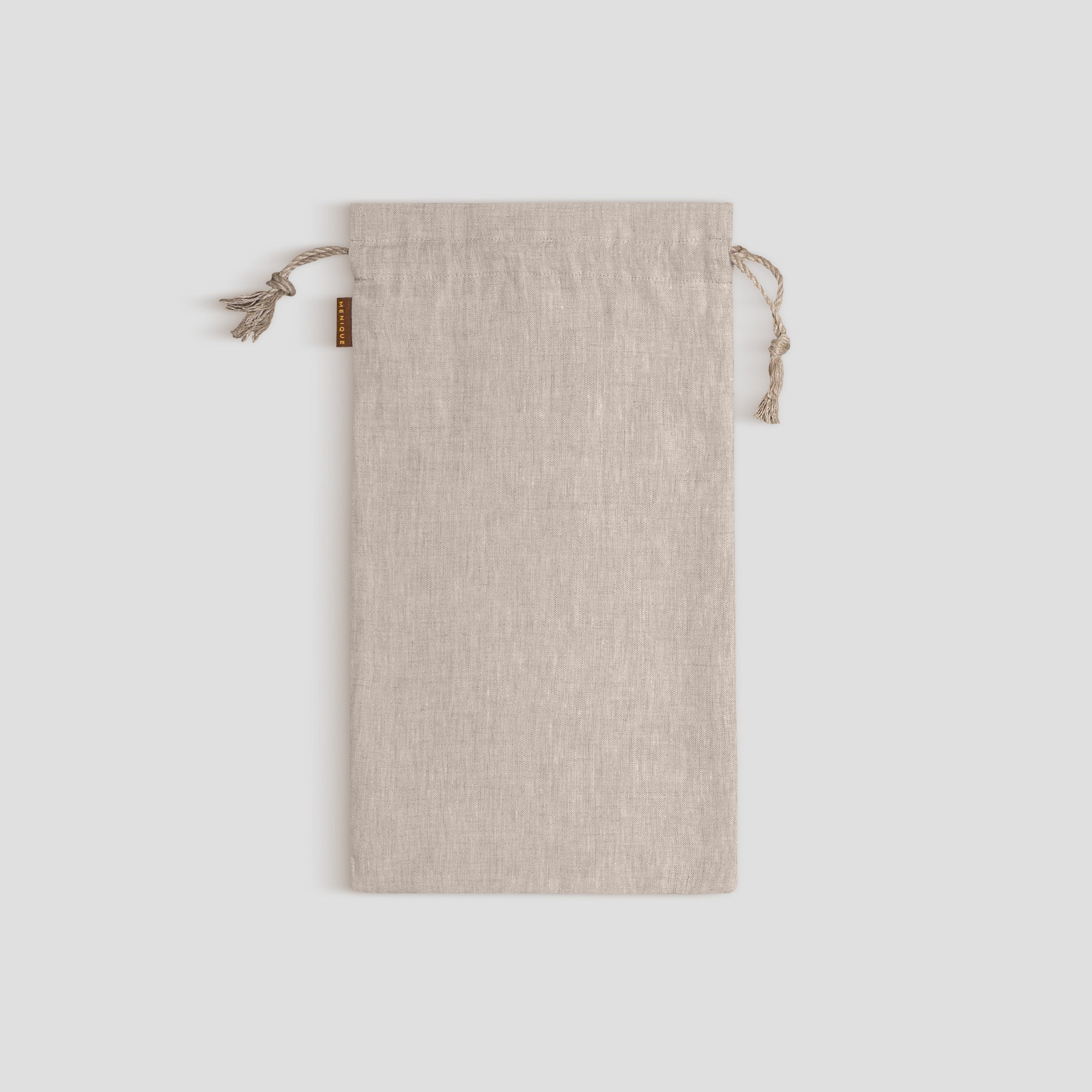 A menique stone green linen drawstring bag stands vertically against a light gray background, its natural twine drawstrings tied.