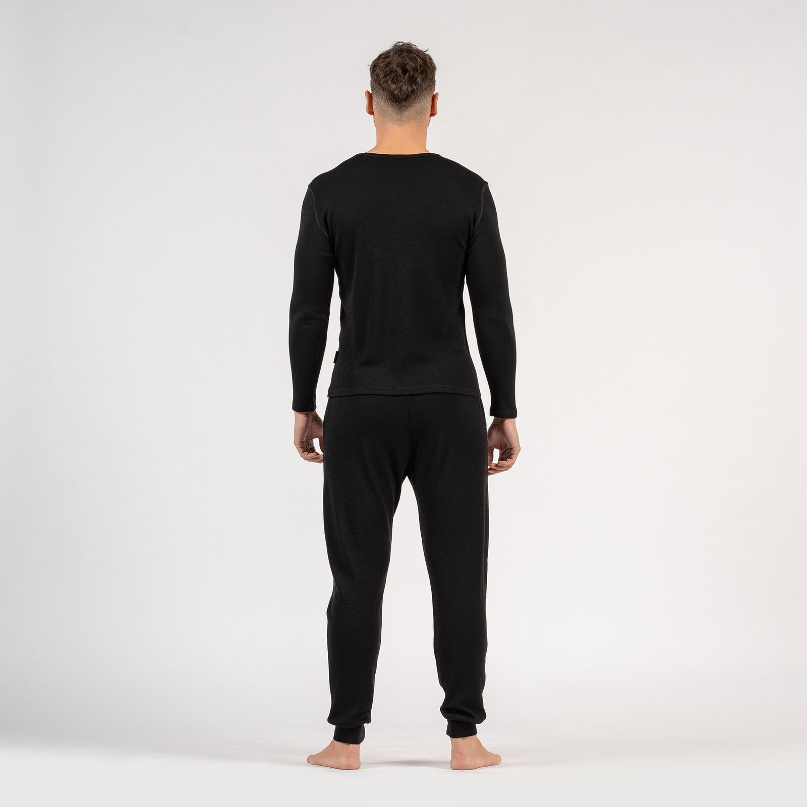 The menique men's merino wool 250gsm long sleeve top and jogger sweatpants set in black color.