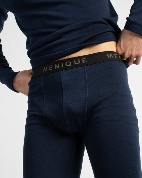 A close-up view of a man's midsection wearing a dark navy thermal base layer top and matching thermal leggings with an elastic waistband.