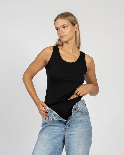 Women’s black Merino wool tank top worn as thermal base layer under jeans, lightweight and breathable