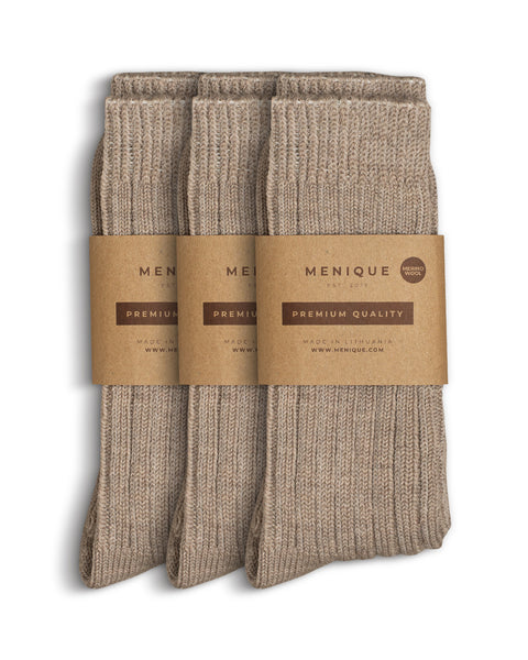 Three pairs of women’s beige ribbed thick socks, neatly folded with Menique brown paper packaging labeled ‘Premium Quality – Merino Wool.
