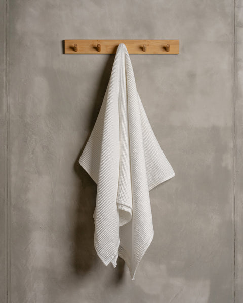 A linen &amp; cotton waffle body towel in pure white color hanging on a wooden rack.