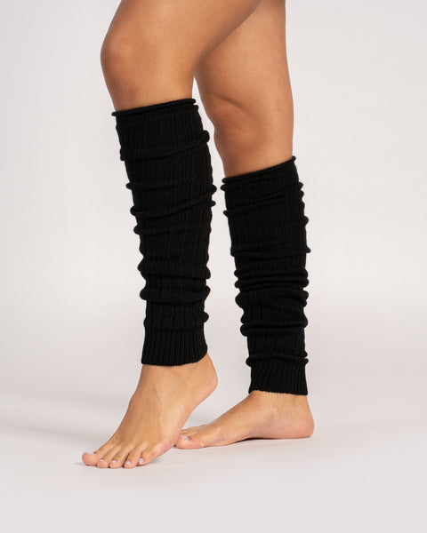 Black leg warmers worn by a person on a white background