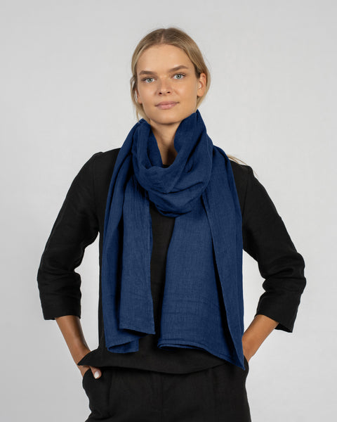 Woman wearing a storm blue menique linen scarf and black outfit on a gray background