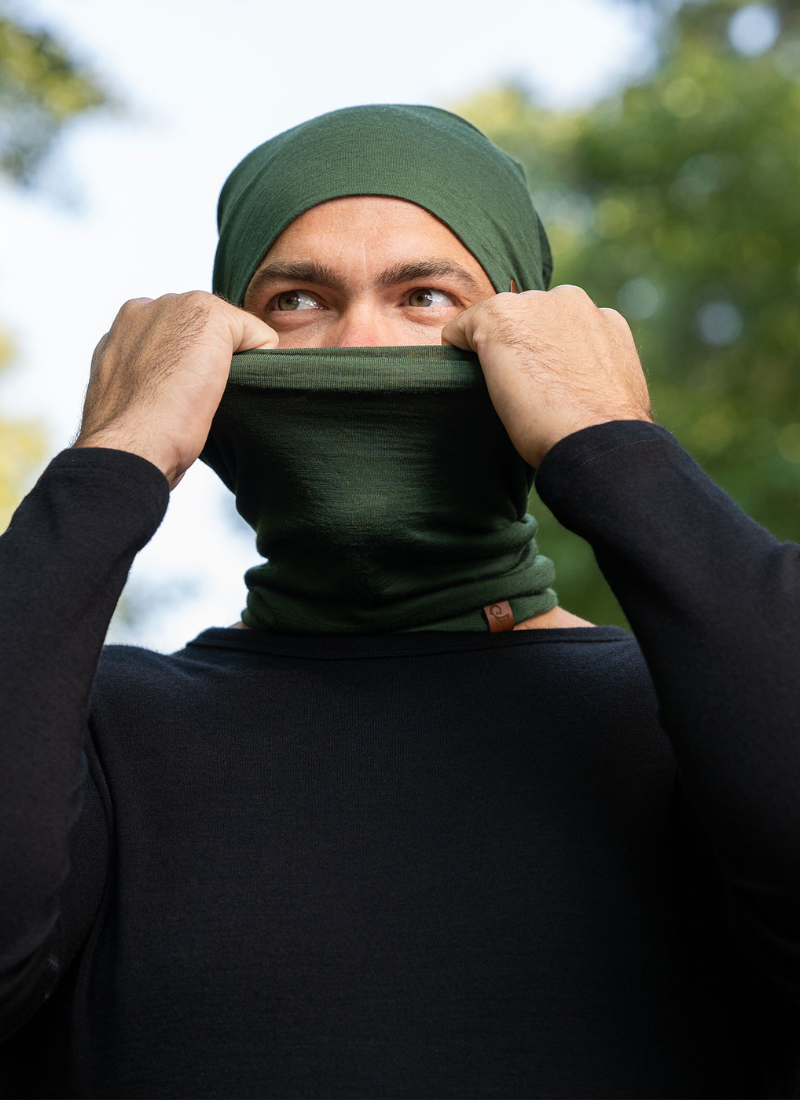 Man outdoors wearing dark green merino wool gaiter and beanie.