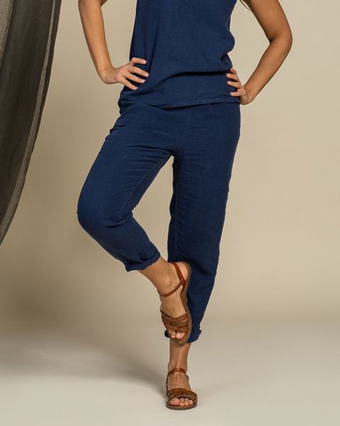 Person wearing a storm blue linen outfit with brown sandals on a neutral background