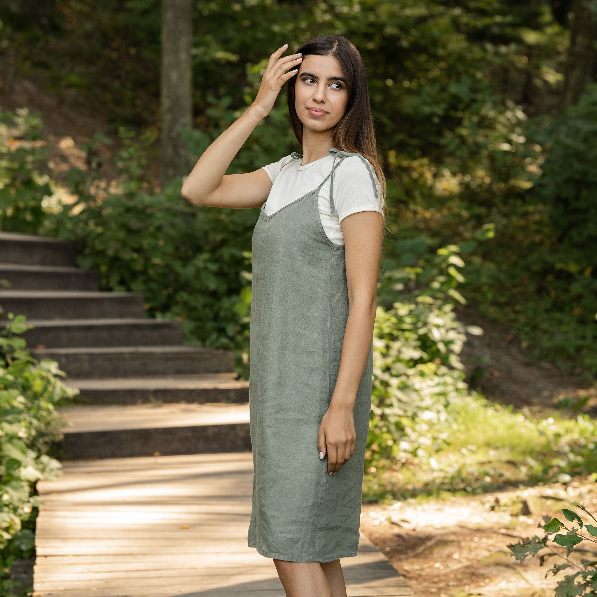 Woman standing in the forest and wearing slip dress from linen 